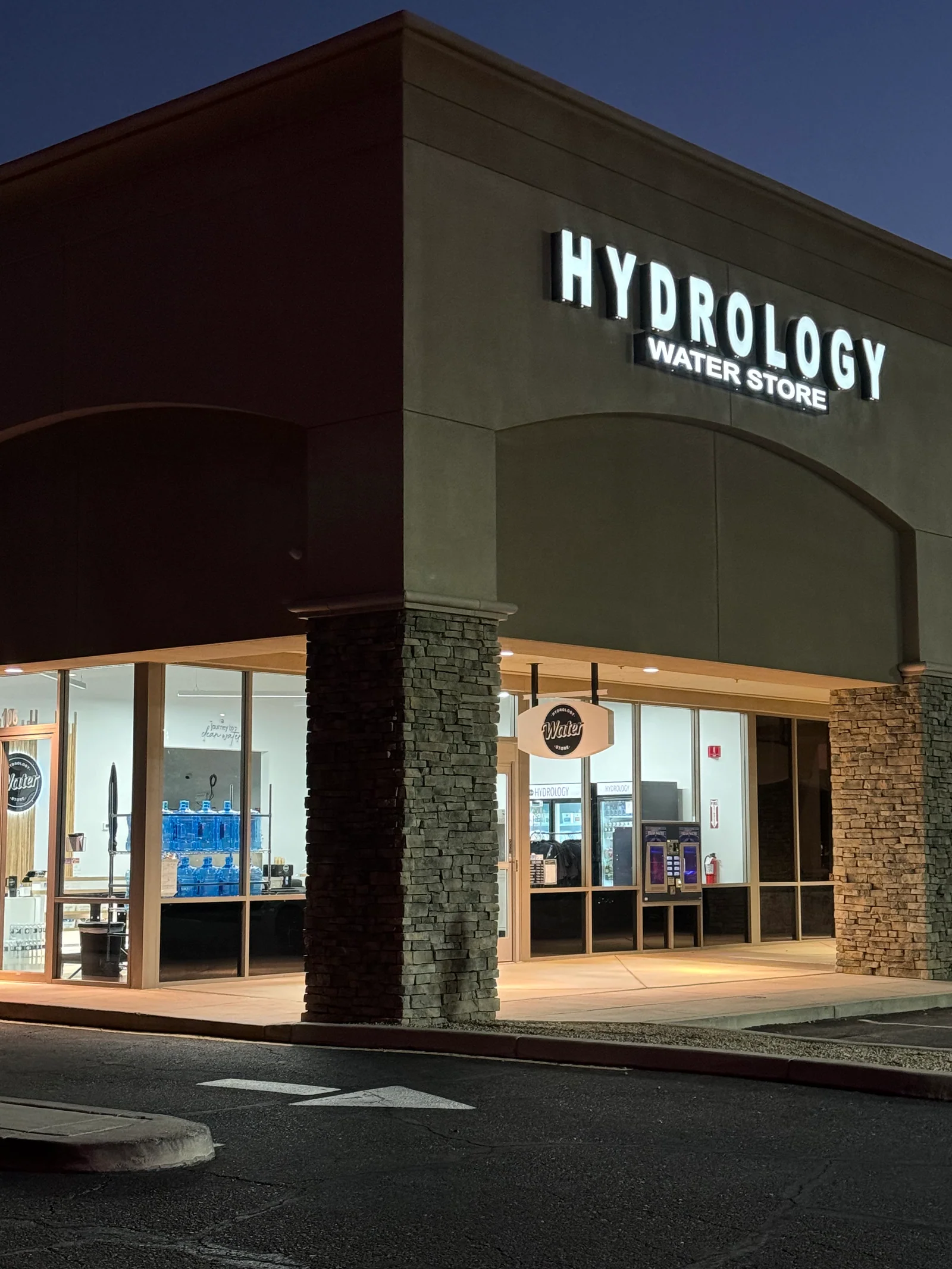 The Hydrology Water Store storefront lit up at night
