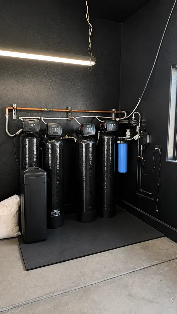 A multi-tank well water filtration and softening system installed in a garage